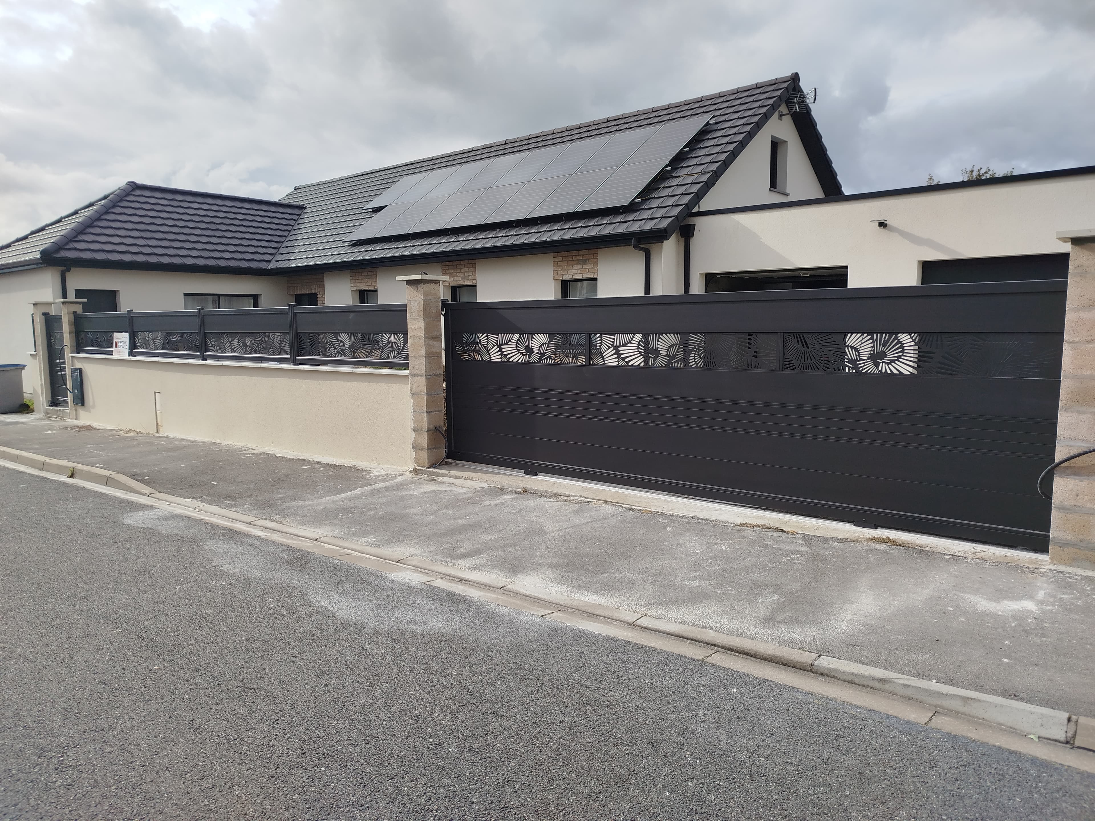 Portail coulissant aluminium anthracite avec motif ajouré posé par Ferm'Opale sur la Côte d'Opale